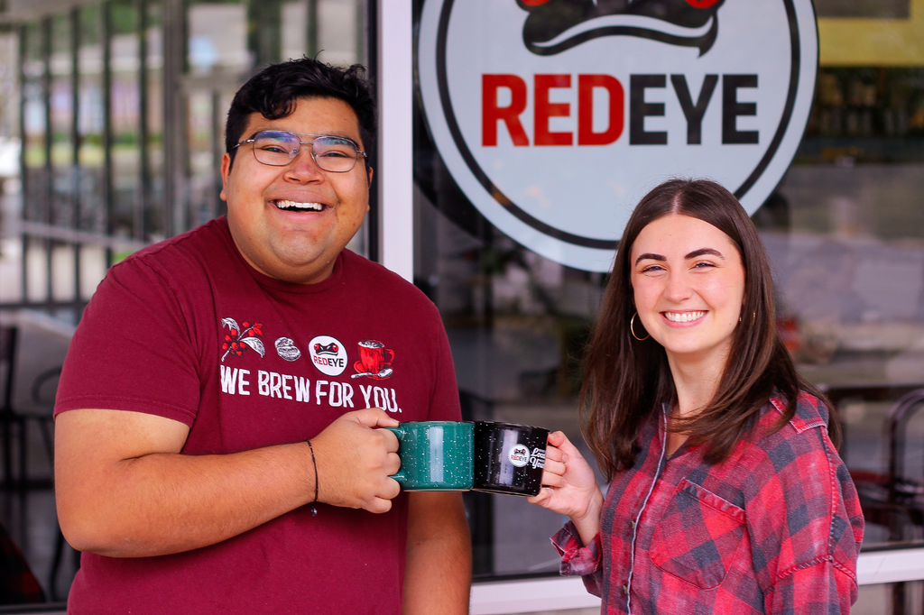 Employees displaying Red Eye mugs at RedEye Coffee in Tallahassee, FL